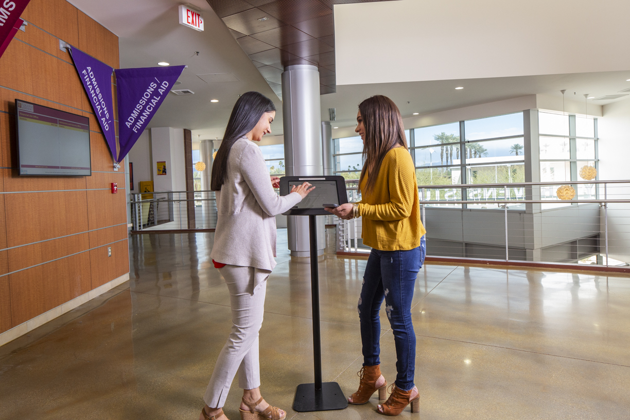 Staff assisting student at kiosk at Cravens